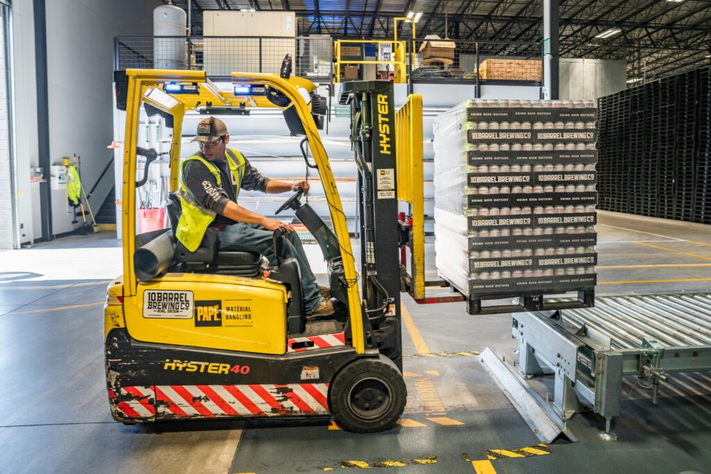 pexels photo 1267338 1267338 A warehouse worker maneuvers a forklift to transport crates for brewing company storage.