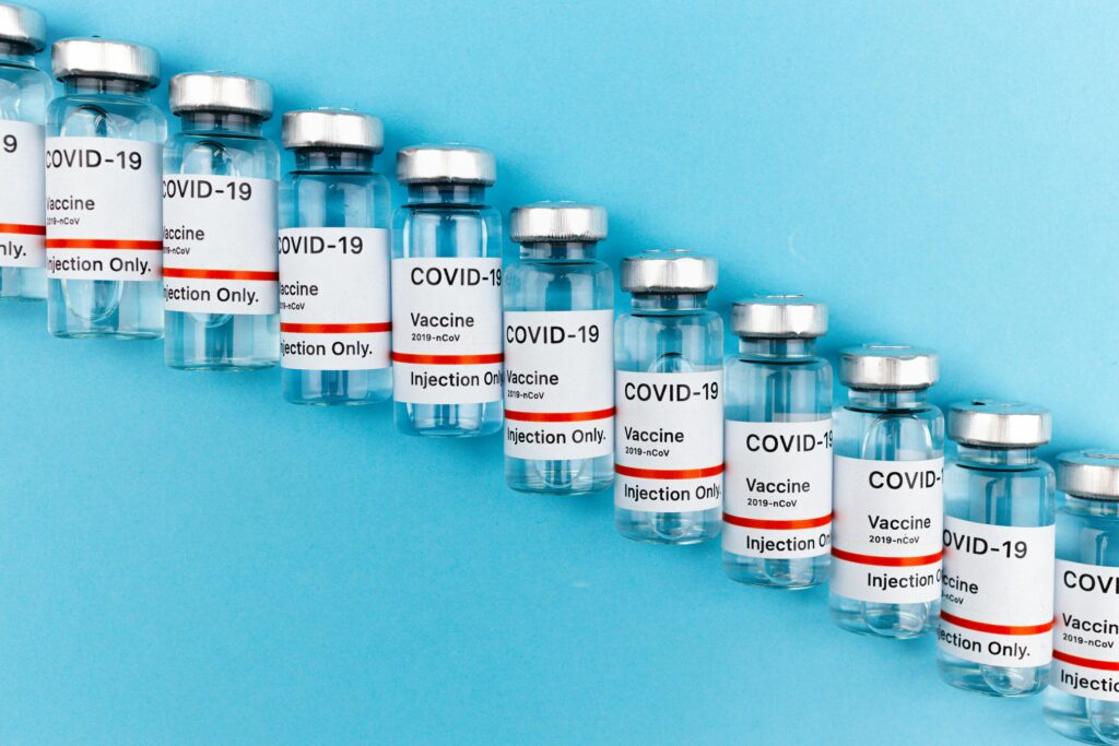 Home Close-up of multiple COVID-19 vaccine vials lined up on a blue surface.